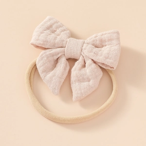 Close-up of soft pink cotton bow and beige elastic nylon headband for infants