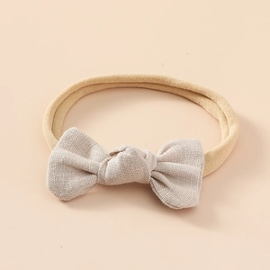 Détail d'un bandeau bébé en nylon souple avec un nœud en lin de couleur beige doux