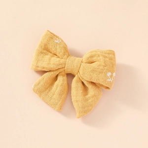 Détail d'un nœud à cheveux en mousseline jaune avec de délicats motifs de cerises