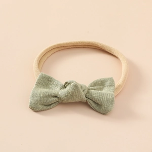 Détail d'un bandeau pour bébé avec nœud en lin vert clair et bande en nylon