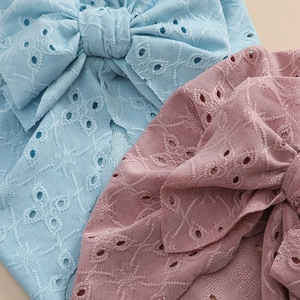 Detail of baby bow headbands featuring intricate eyelet embroidery in blue and pink cotton