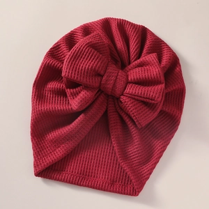 Close-up of dark red waffle knit texture and large bow detail on baby beanie cap