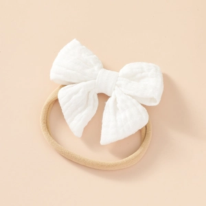 Detail of soft white muslin cotton bow on stretchable nylon headband for newborns