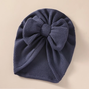 Detailed texture of dark blue waffle knit baby turban hat with oversized bow