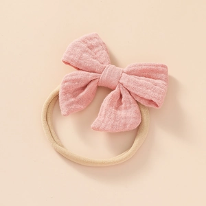 Detailed close-up of a soft pink cotton linen bow with elastic nylon headband for babies