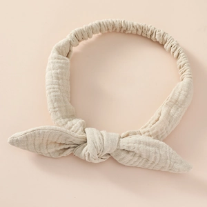 Detailed texture of beige cotton bow headband for baby with elastic back design