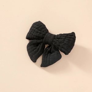 Détail de la pince à cheveux noeud en mousseline de coton noir avec texture douce