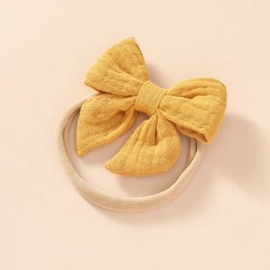 Detailed view of ginger cotton bow and soft elastic nylon headband for newborns