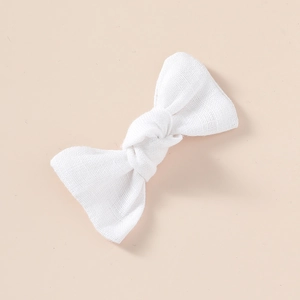 Vue détaillée de la texture en lin et du nœud d'une barrette à cheveux en tissu blanc