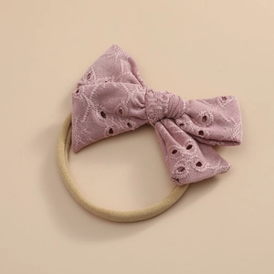 Détail d'un bandeau en dentelle pour bébé avec ruban nylon souple et motif ajouré complexe