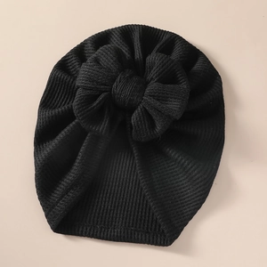 Detailed view of black knitted baby turban hat with a large textured 3D bow design