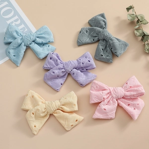 Vue à plat de cinq barrettes à nœuds en dentelle brodée pour filles en tons pastel