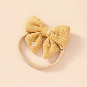 Close-up of soft nylon baby headband with yellow cherry pattern bow detail
