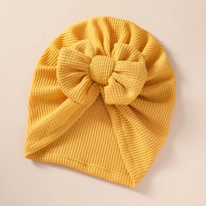 Close-up of yellow baby turban hat with oversized bow and textured waffle knit fabric