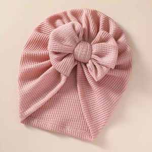 Macro detail of baby pink waffle knit turban hat with a large bow decoration