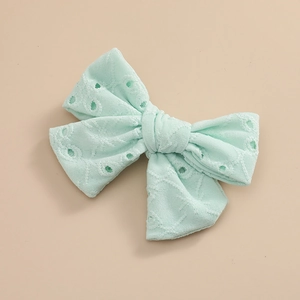Détail de la broderie anglaise vert menthe sur une pince à cheveux avec nœud en tissu
