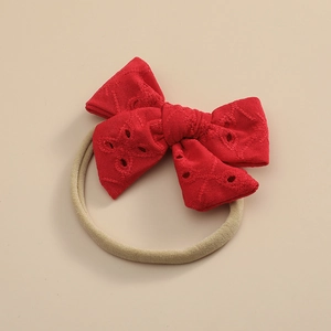 Détail du nœud en dentelle rouge ajourée sur un bandeau de bébé en nylon élastique doux