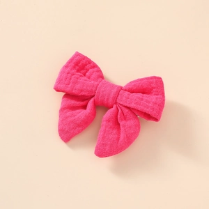 Vue détaillée de la pince à cheveux nœud papillon en mousseline de coton magenta pour fille