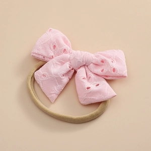 Détail du bandeau bébé avec nœud en dentelle rose et broderie florale sur nylon doux