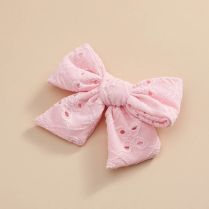 Détail macro de la texture de broderie florale rose sur une pince à nœud pour fille