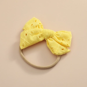 Détail du nœud en dentelle brodée jaune sur un bandeau pour bébé en nylon élastique souple
