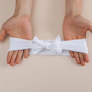 Elastic white baby headbands with large bow detail showing high stretch nylon fabric