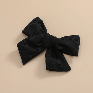 Détail de la pince à cheveux noire avec broderie anglaise délicate et texture tissu