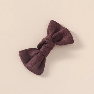 Vue détaillée d'une pince à cheveux nœud en lin violet foncé avec texture tissée