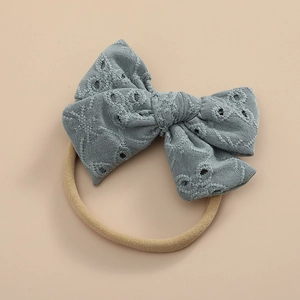 Détail du nœud en dentelle bleue sur un bandeau de bébé en nylon doux et élastique