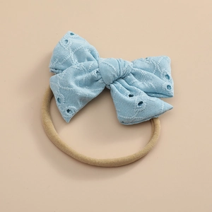 Détail du nœud en dentelle bleu clair brodé sur un bandeau élastique pour bébé