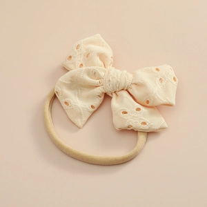 Détail du bandeau en dentelle crème avec nœud et ruban en nylon souple pour bébés