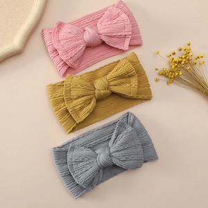 Detail view of soft elastic nylon baby headbands with large bows in pink, yellow and grey