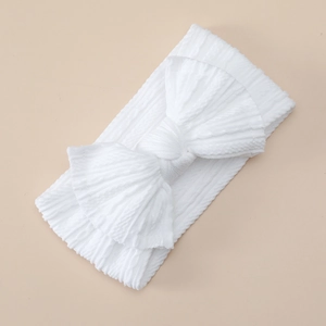 Detail of soft white waffle texture nylon headband with large bow for infants