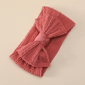 Detail of soft ribbed nylon baby headband with a large coral pink decorative bow