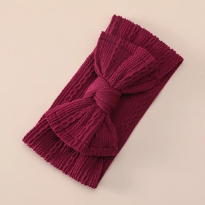 Detail showing deep red cable knit nylon baby headband with large decorative bow texture