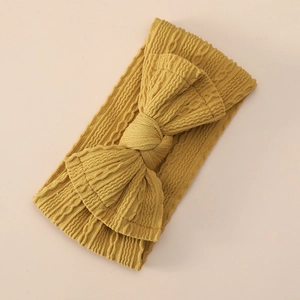 Detail of ginger yellow knitted nylon headband with a large handmade bow for infants