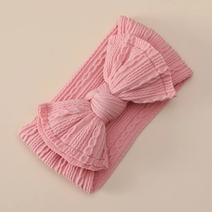 Close-up of pink ribbed nylon baby headband with a large soft decorative bow