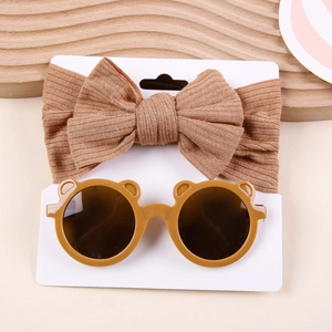 Close-up of brown ribbed knit bow headband and bear shaped sunglasses set for babies