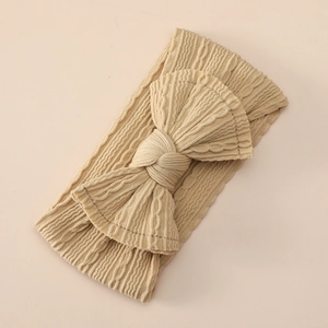 Detailed view of the soft beige jacquard knit texture on a wide baby nylon headband