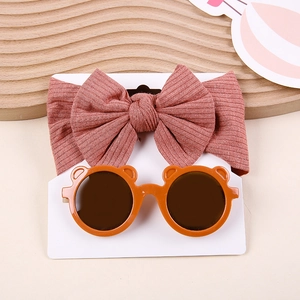 Detail of baby set with brick red bow headband and orange bear-eared sunglasses