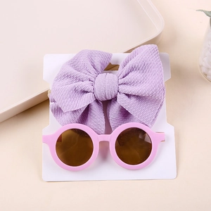 Close-up of a purple waffle bow headband and pink round sunglasses for toddlers