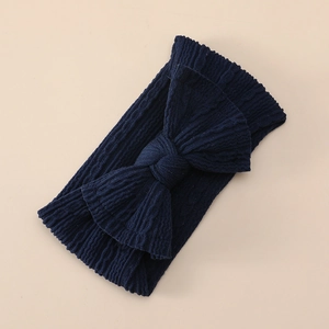 Detailed view of dark blue ribbed knit baby headband with a large decorative bow