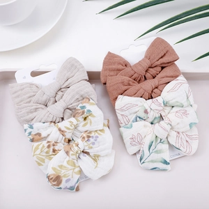 4-pack cotton muslin bow hair clips for infants featuring floral and solid neutral patterns