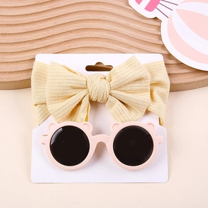 Detail of yellow ribbed bow headband and pink bear-eared sunglasses for kids on display card
