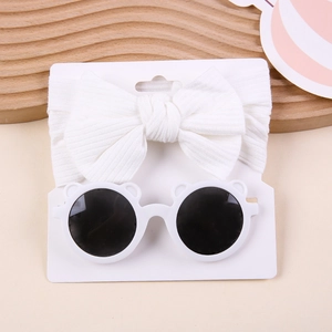 White baby headband with ribbed bow and bear-shaped sunglasses set on card display