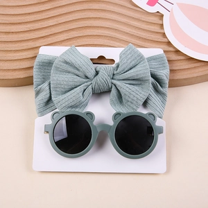 Detail view of sage green ribbed bow headband and bear ear sunglasses on display card