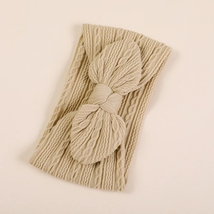 Vue détaillée montrant la texture en tricot d'un bandeau beige à nœud pour bébé en nylon