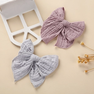 Close-up of two muslin cotton hair bows in dusty pink and light grey blue colors