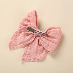 Detail of baby hair clip showing silver metal alligator clip and pink cotton fabric texture