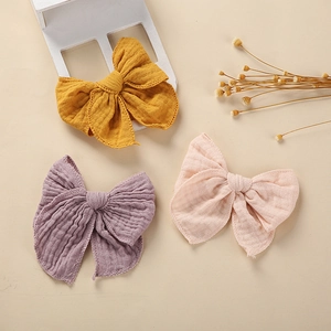 Three-pack of cotton muslin hair bows for babies in mustard, pink, and grey-purple colors